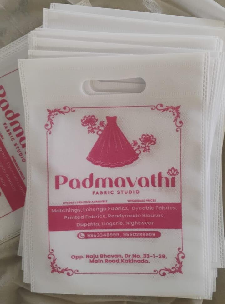 Stack of pink non-woven D-cut bags for Padmavathi Fabric Studio